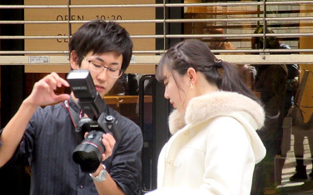 カメラマンからレクチャーを受ける佐藤さん