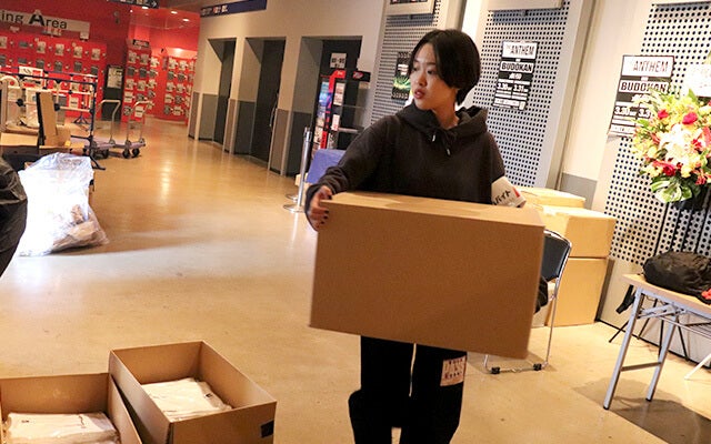 段ボールを持ち必要なグッズを準備する小栁さん