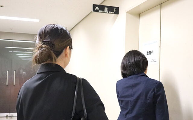 スタッフさんと一緒に楽屋に入る田中さん