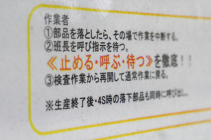 工場の作業台近くに貼られている「止める・呼ぶ・待つ」に関する資料