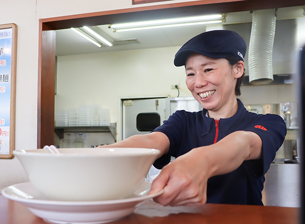 笑顔で料理を提供している主婦Oさん