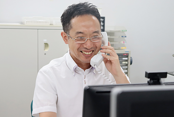 登録スタッフからの電話に笑顔で対応する大阪支店・支店長Kさん