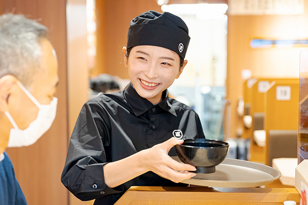 味噌汁を提供しているスタッフ