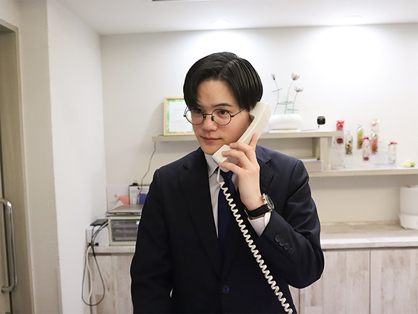 ホテルのフロントスタッフが電話応対する様子